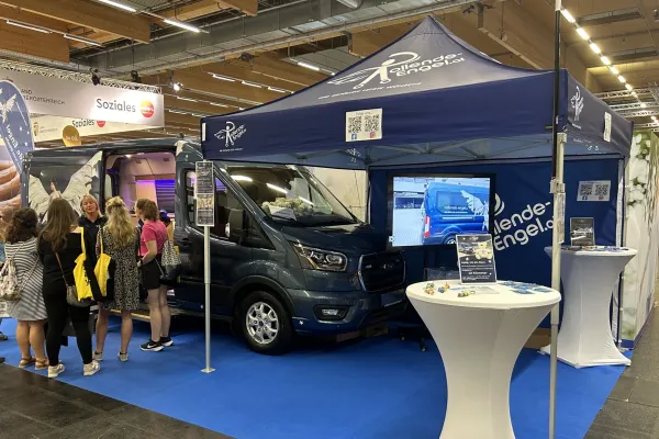 Bedrucktes Messezelt mit Beachflag in der Messehalle – Rollende Engel