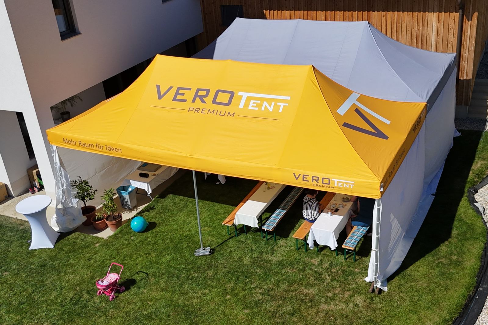 Gelbes VeroTENT Faltzelt 4x8 m beim Gartenfest, Drohnenaufnahme
